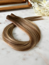 Load image into Gallery viewer, Angled view of the Amanda warm bronde hybrid hair extension weft