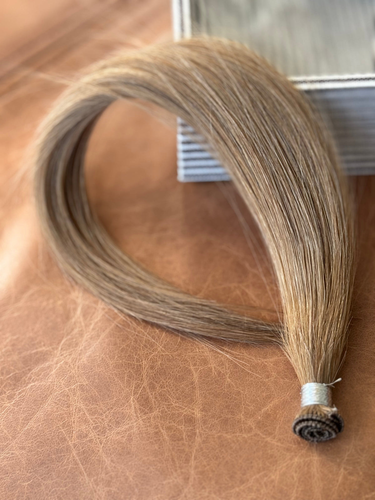 Chai Tea dirty blonde hand-tied hair extension weft with the rolled seam in focus