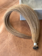 Load image into Gallery viewer, Chai Tea dirty blonde hand-tied hair extension weft with the rolled seam in focus