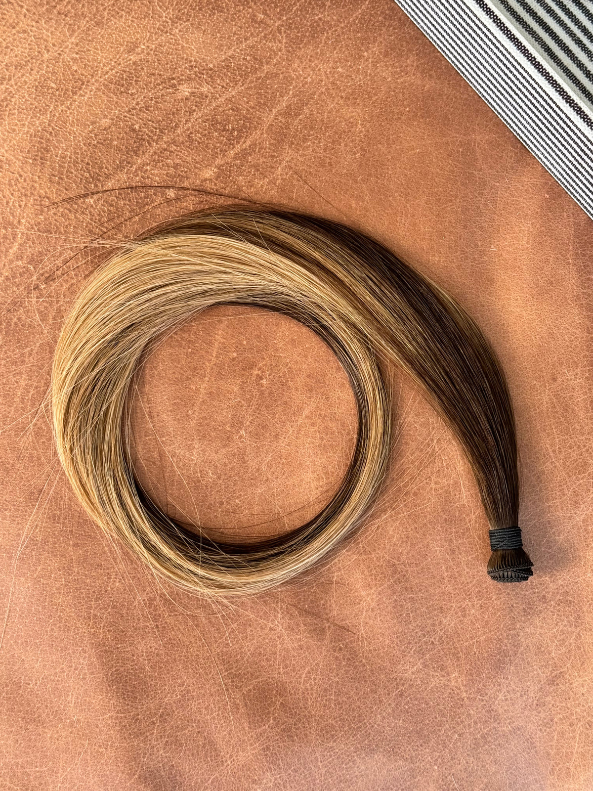 Kallee hand tied hair weft arranged in a full loop on a warm neutral background