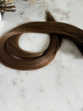 Load image into Gallery viewer, Close view of the Megan Hybrid Weft 22-inch rooted brunette hair texture